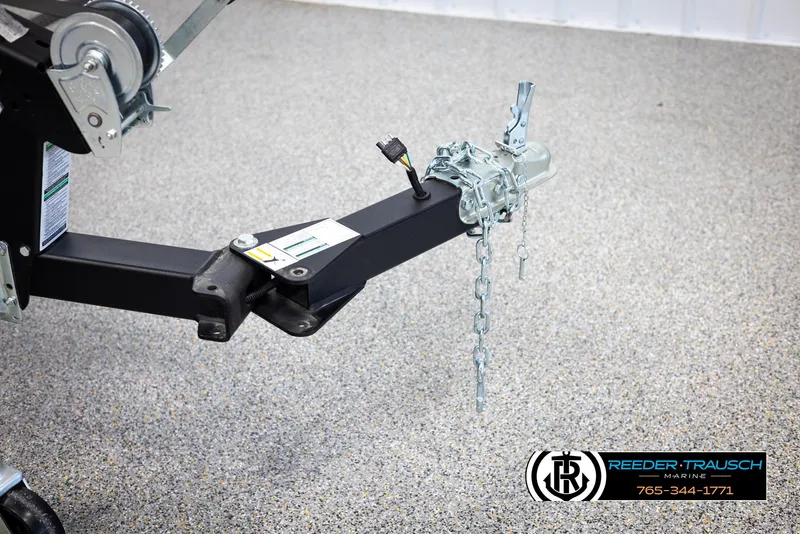 Slide: The Image of Trailer hitch of 2025 Lund Rebel XL SS with safety chains on a speckled floor. - 40