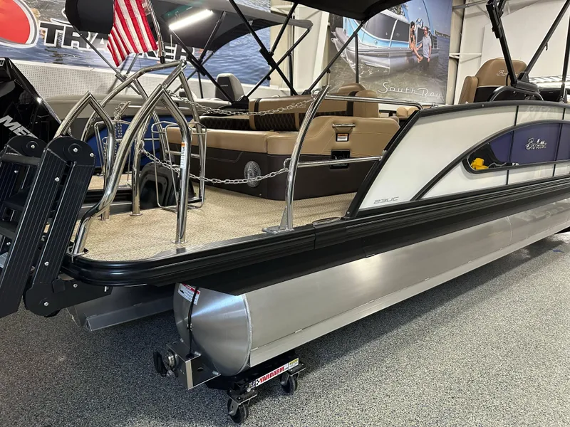 Slide: The Image of 2025 Barletta Lusso 23UC pontoon boat displayed indoors with American flag. - 2