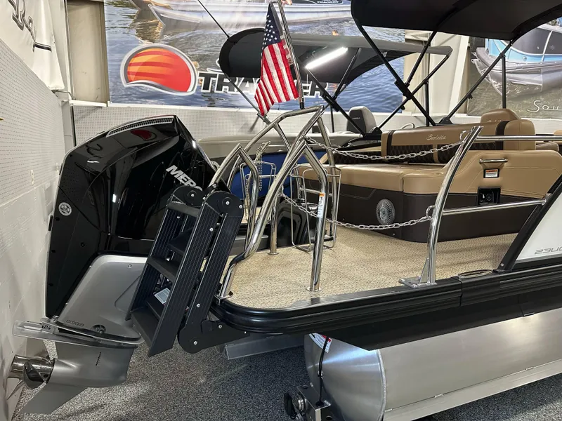 Slide: The Image of 2025 Barletta Lusso 23UC pontoon boat with Mercury engine and American flag display. - 3