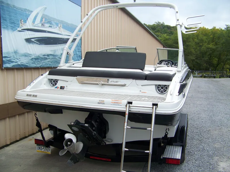 Slide: The Image of 2019 Crownline 215SS boat with swim platform and ladder, parked near a building. - 3