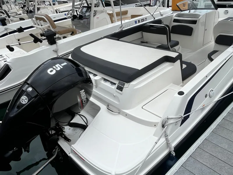 Slide: The Image of 2021 Bayliner VR6 Bowrider OB with spacious seating and modern dashboard at a marina. - 4