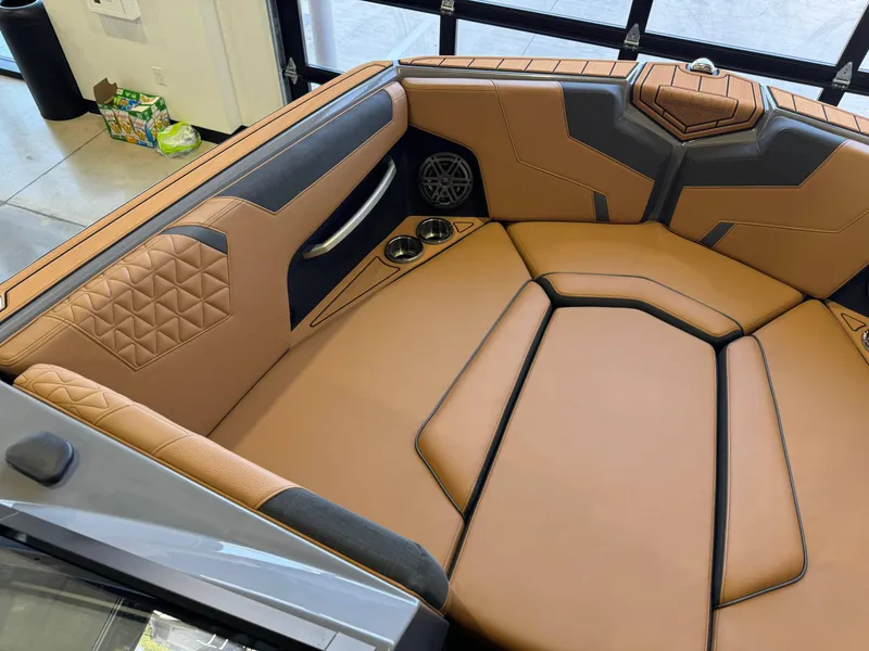 Slide: The Image of 2025 Nautique Super Air Nautique GS24 interior with tan upholstery and cup holders. - 19