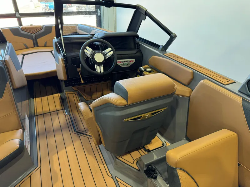 Slide: The Image of 2025 Nautique Super Air Nautique GS24 interior with tan and gray seating, modern dashboard. - 24