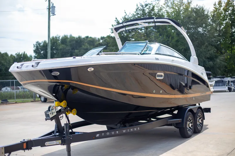 The Image of 2025 Four Winns HD5 boat on trailer, sleek design, black and gold accents. - 1