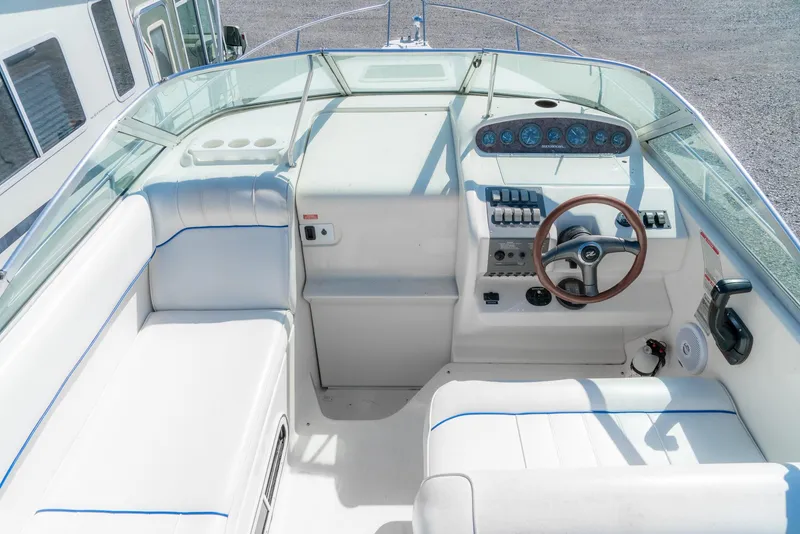 Slide: The Image of 1995 Sea Ray 250 Sundancer cockpit with white seating and wooden steering wheel. - 14