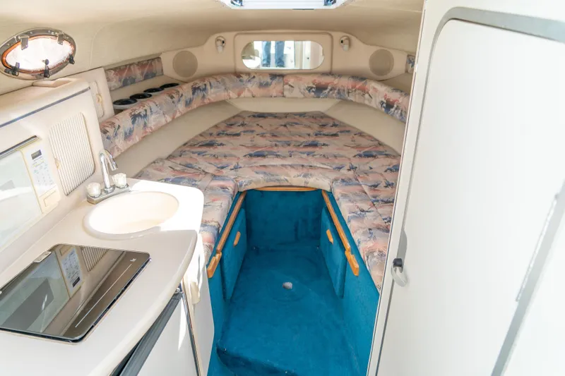 Slide: The Image of Interior of 1995 Sea Ray 250 Sundancer boat with kitchenette and cozy sleeping area. - 19