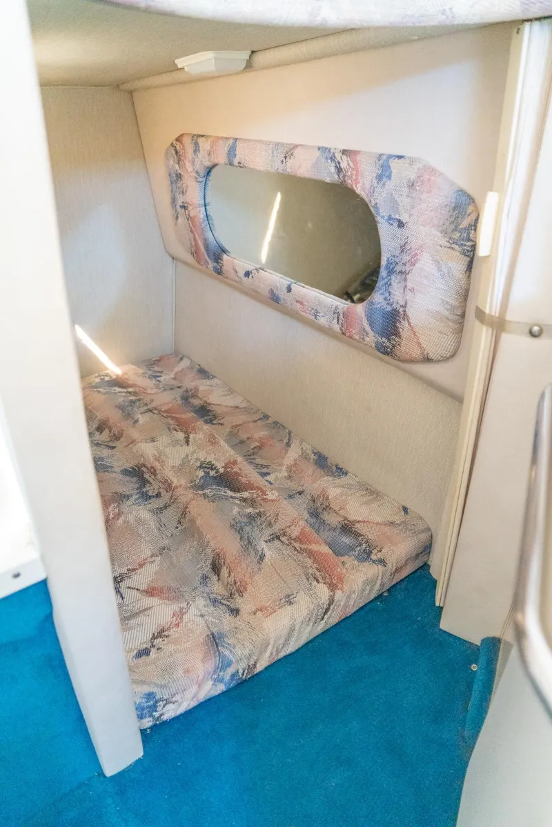 Slide: The Image of 1995 Sea Ray 250 Sundancer cabin interior with bed and window, featuring blue carpet. - 22