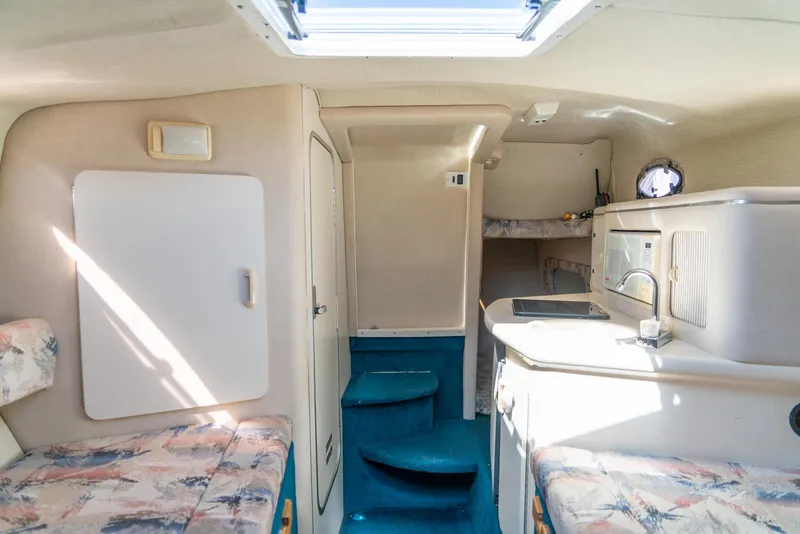 Slide: The Image of Interior of a 1995 Sea Ray 250 Sundancer boat, featuring a compact kitchen and seating area. - 24