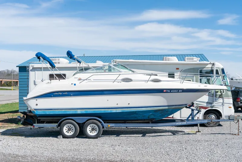 Slide: The Image of 1995 Sea Ray 250 Sundancer boat on trailer, parked beside RV, under clear blue sky. - 3