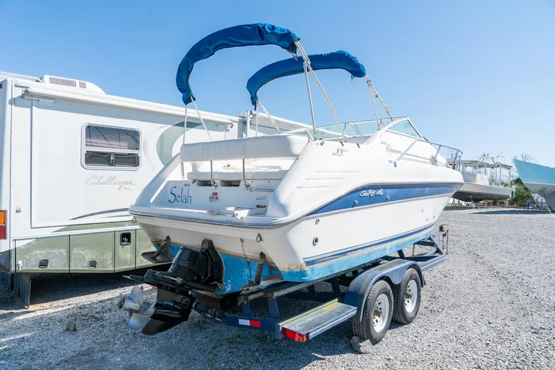 Slide: The Image of 1995 Sea Ray 250 Sundancer boat on trailer, parked beside an RV. - 6