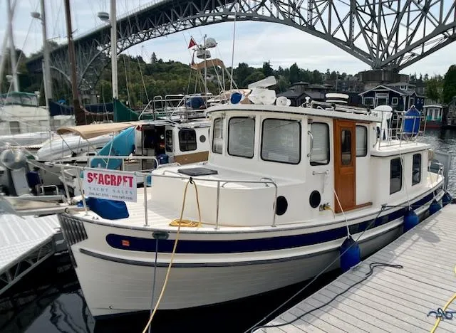 The Image of 1989 Nordic Tug 32 docked near a bridge, showcasing classic design and sturdy build. - 0