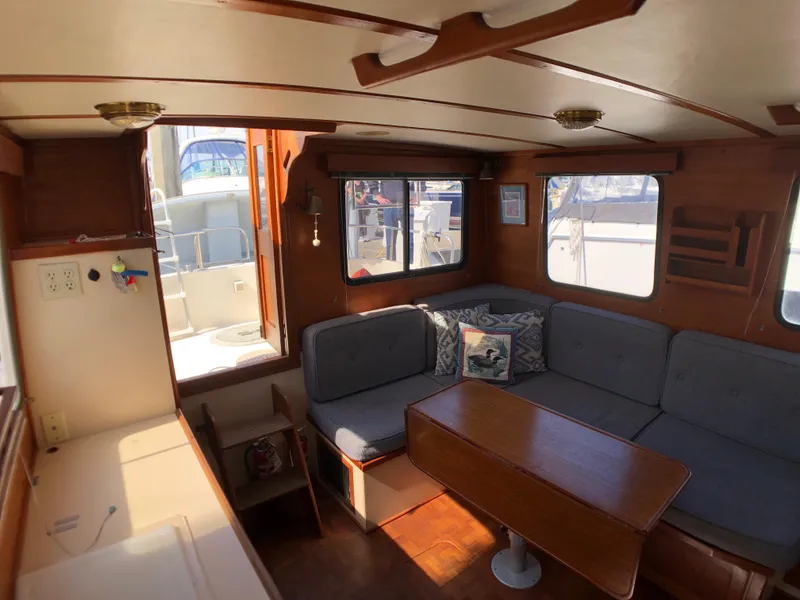 Slide: The Image of Cozy interior of 1989 Nordic Tug 32 with seating and table, featuring wood accents. - 15