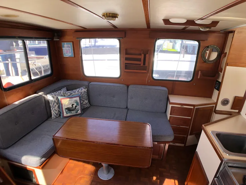 Slide: The Image of Cozy interior of 1989 Nordic Tug 32 with wooden furnishings and cushioned seating. - 16