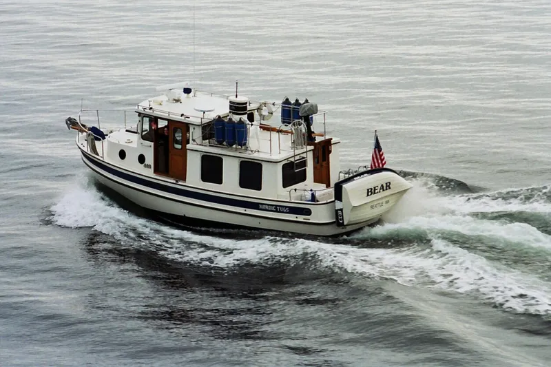 Slide: The Image of 1989 Nordic Tug 32 cruising on calm waters with American flag. - 2