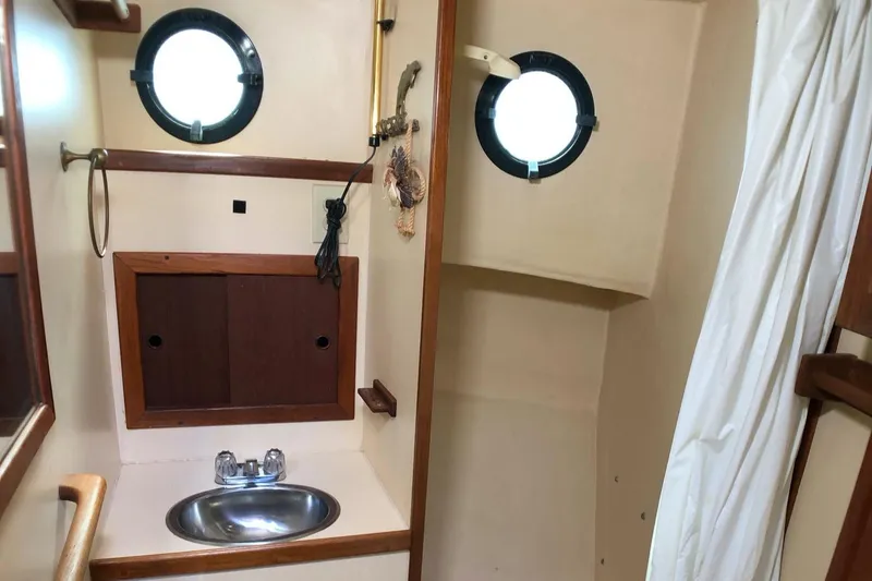 Slide: The Image of 1989 Nordic Tug 32 bathroom with portholes, sink, and wooden cabinetry. - 23