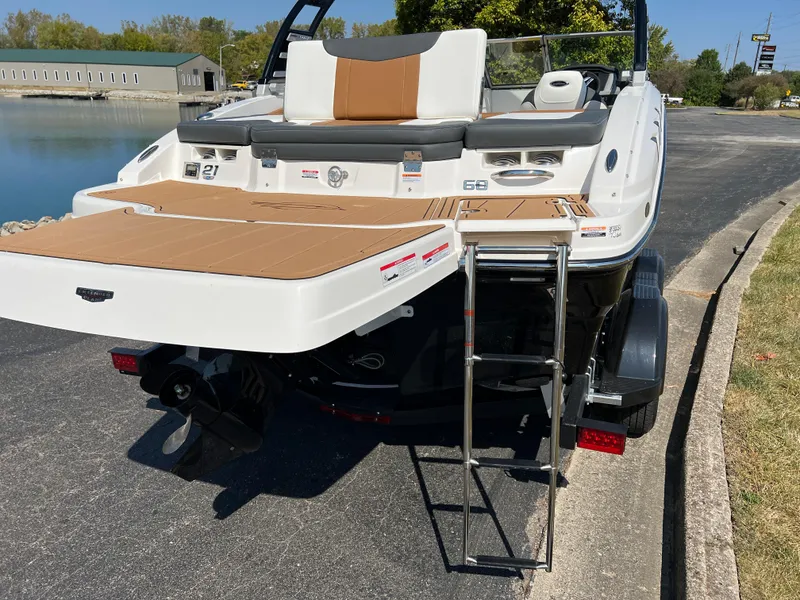 Slide: The Image of 2025 Chaparral 21 SSi boat with swim platform and ladder, parked near a lake. - 8