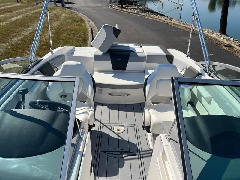 Slide: The Image of 2025 Chaparral 21 SSi boat interior with seating and steering wheel, docked by a calm lake. - 17