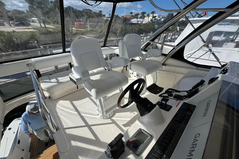 Slide: The Image of 2008 Sea Ray 58 Sedan Bridge helm with white captain chairs and Garmin navigation system. - 20