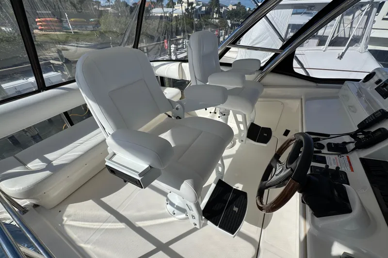 Slide: The Image of 2008 Sea Ray 58 Sedan Bridge helm with white captain chairs and control panel. - 21