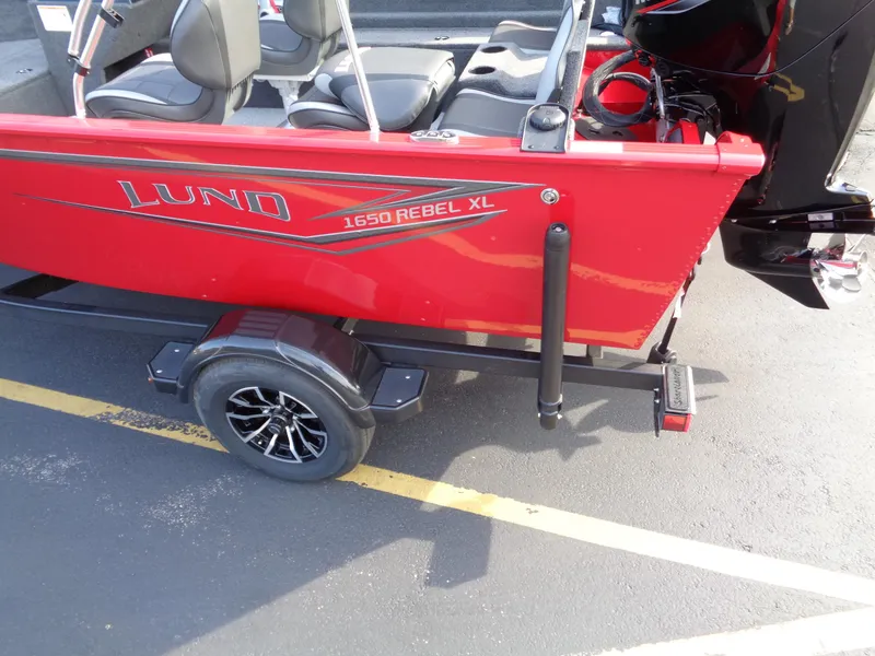 Slide: The Image of 2025 Lund 1650 Rebel XL SS boat, red exterior, on trailer in parking lot. - 5