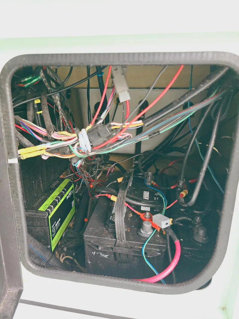 Slide: The Image of 2021 Excel Bay Pro boat battery compartment with wiring and connections. - 13