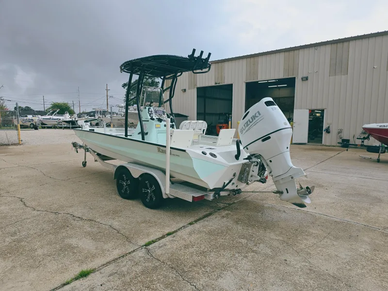 Slide: The Image of 2021 Excel Bay Pro boat with outboard motor on trailer, parked outside a warehouse. - 4
