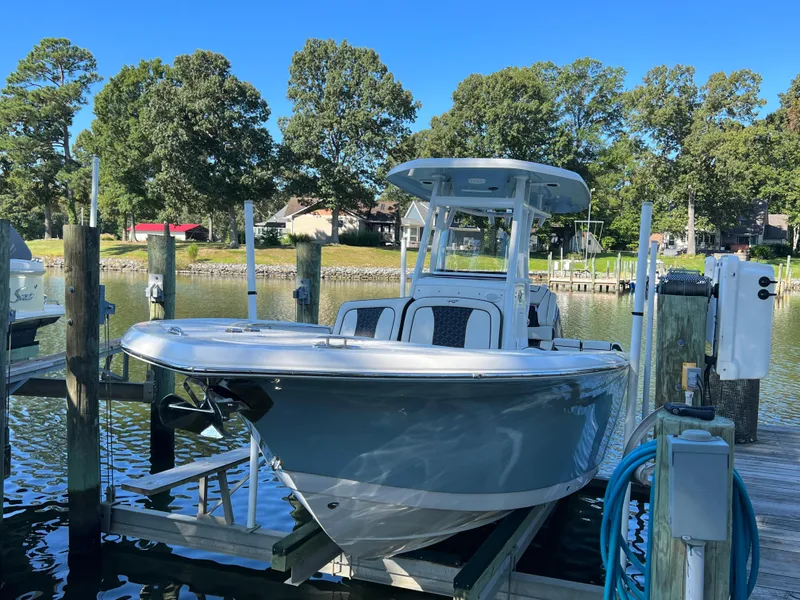 The Image of 2021 Tidewater 232 LXF boat docked on a sunny day, surrounded by trees and calm water. - 0