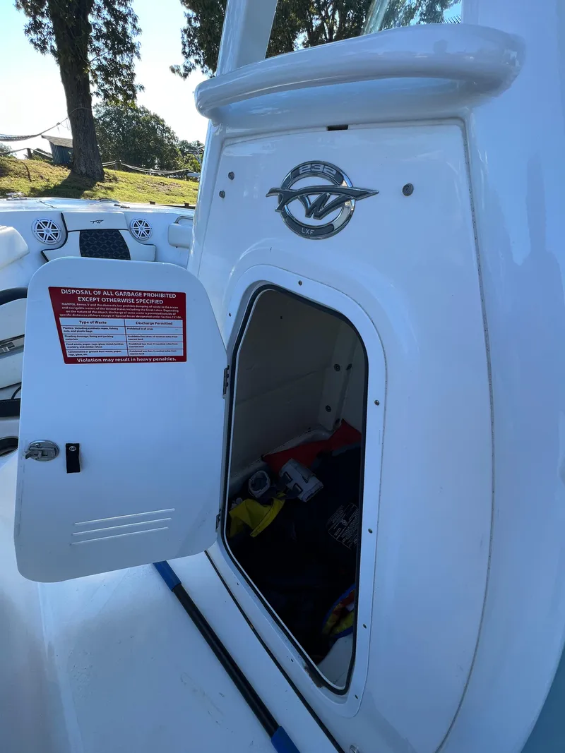 Slide: The Image of 2021 Tidewater 232 LXF boat storage compartment with open door, showing interior and warning label. - 11