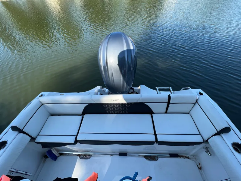 Slide: The Image of 2021 Tidewater 232 LXF boat with cushioned seating and outboard motor on calm water. - 12