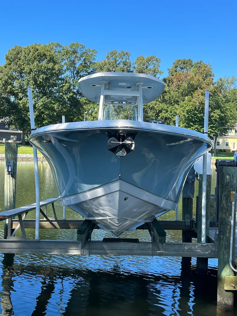 Slide: The Image of 2021 Tidewater 232 LXF boat on lift, surrounded by trees and water. - 2