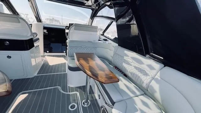 Slide: The Image of 2023 Sea Ray 370 Sundancer interior with elegant seating and wooden table. - 10