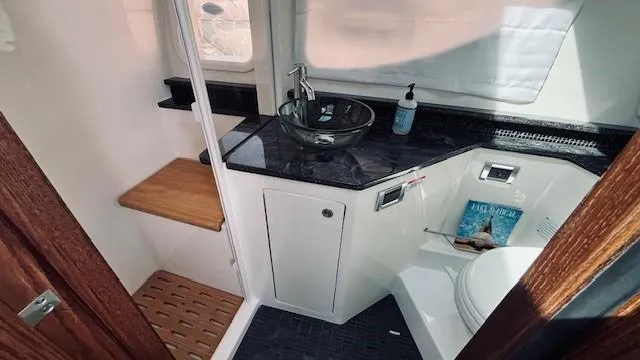 Slide: The Image of 2023 Sea Ray 370 Sundancer bathroom with modern sink, toilet, and wooden accents. - 20