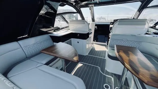 Slide: The Image of 2023 Sea Ray 370 Sundancer interior with elegant seating and wooden tables. - 9