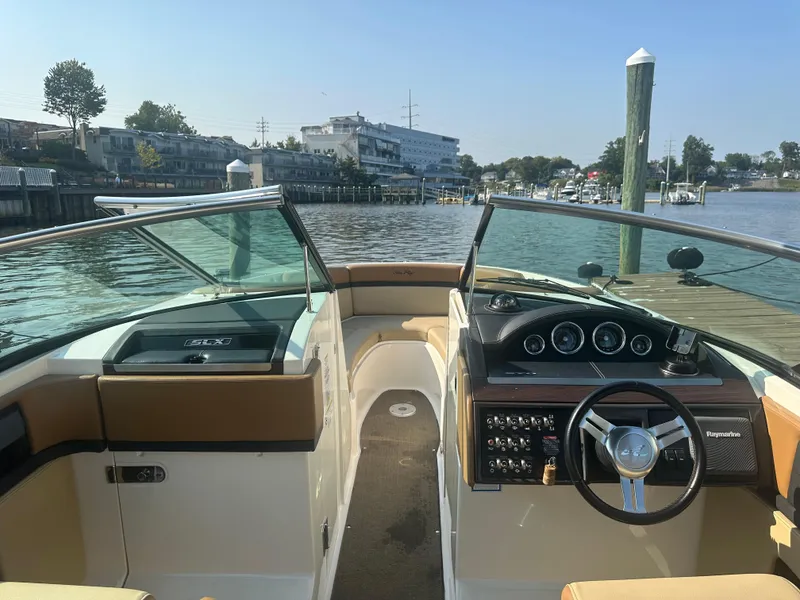 Slide: The Image of 2014 Sea Ray 270 SLX boat interior with steering wheel, docked by a scenic waterfront. - 12