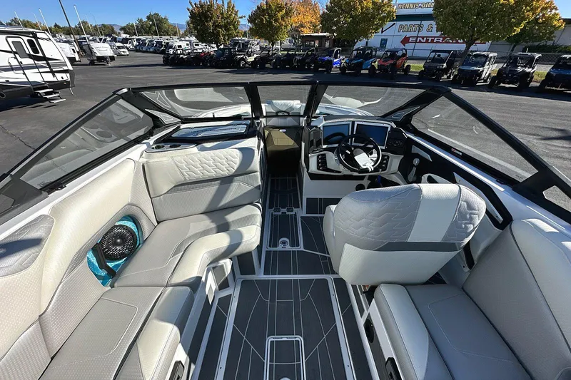 Slide: The Image of 2024 Centurion Ri230 boat interior with modern seating and dashboard, parked outdoors. - 5