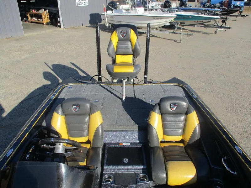 Slide: The Image of 2016 Triton 20 TRX boat interior with black and yellow seats, docked outdoors. - 6
