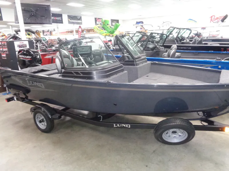 The Image of 2024 Lund 1650 Angler SS boat in red on a trailer, parked outdoors. - 0