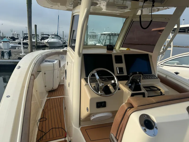 Slide: The Image of 2015 Scout 320 LXF boat interior with steering wheel and control panel at marina. - 10