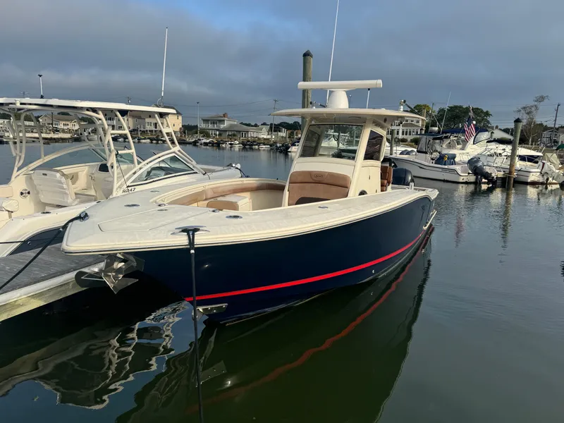 Slide: The Image of 2015 Scout 320 LXF boat docked in a marina, surrounded by other vessels. - 12