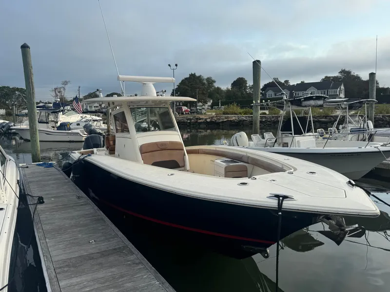 Slide: The Image of 2015 Scout 320 LXF boat docked at marina, calm water, overcast sky. - 17