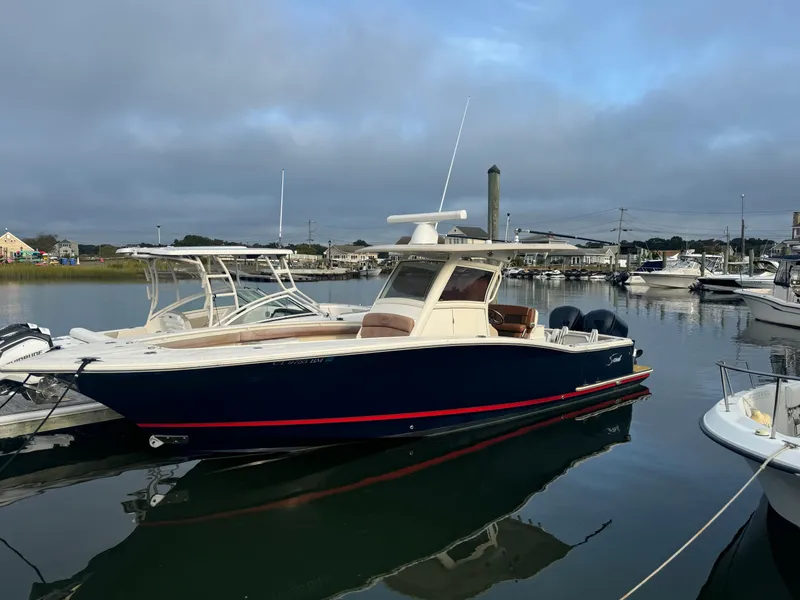 Slide: The Image of 2015 Scout 320 LXF boat docked in a marina, calm water, overcast sky. - 18