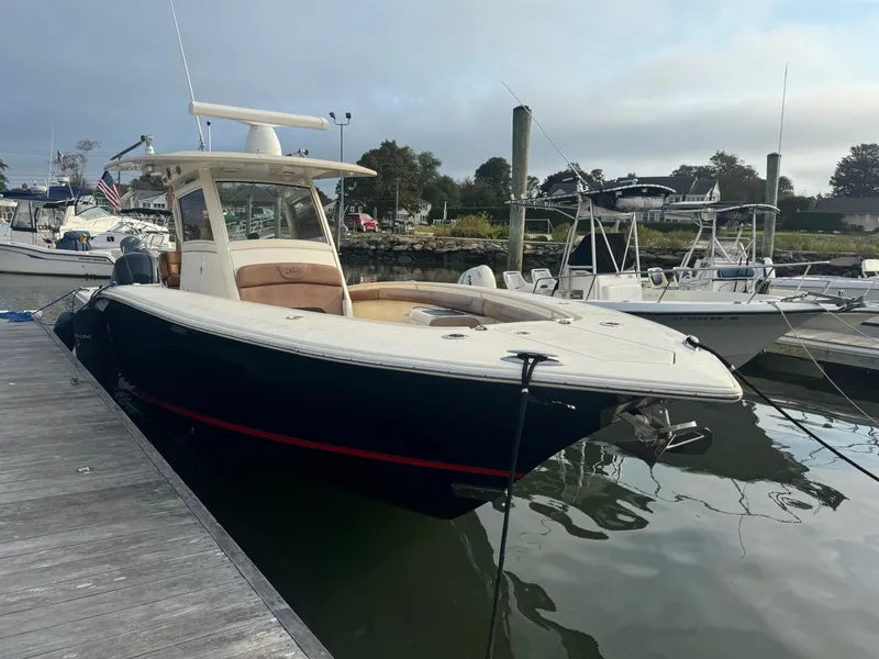 Slide: The Image of 2015 Scout 320 LXF boat docked at marina, sleek design, calm water. - 3