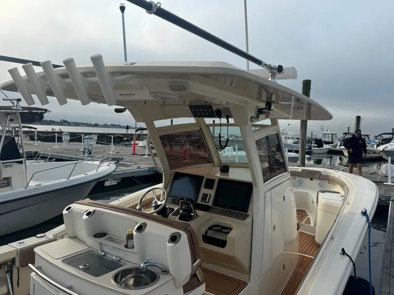 Slide: The Image of 2015 Scout 320 LXF boat docked, featuring a modern helm and spacious deck. - 7