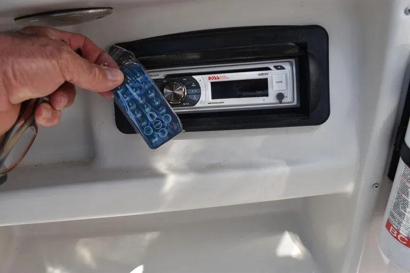 Slide: The Image of Hand holding remote near stereo on 2003 Hurricane SD 187 boat dashboard. - 35
