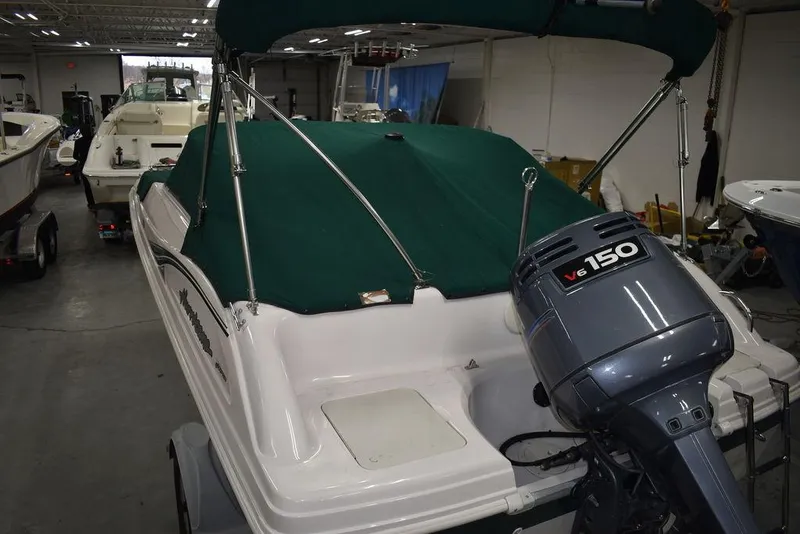 Slide: The Image of 2003 Hurricane SD 187 boat with green canopy and V6 150 outboard motor in a showroom. - 44