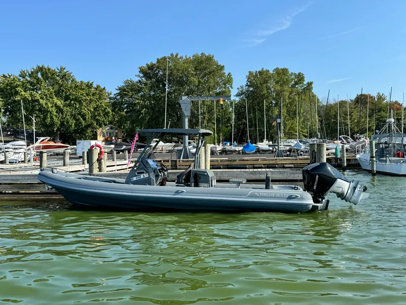 Slide: The Image of 2024 Highfield Sport 900 boat docked in a marina, surrounded by trees and other boats. - 1