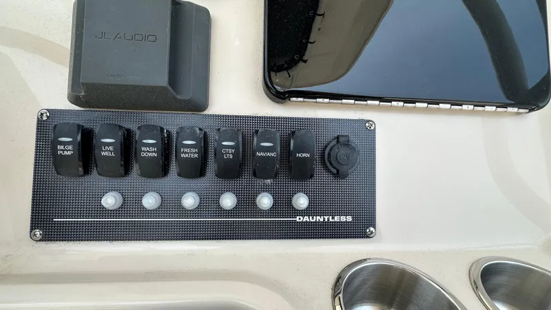 Slide: The Image of Control panel of 2025 Boston Whaler 220 Dauntless boat with various switches and JL Audio system. - 12