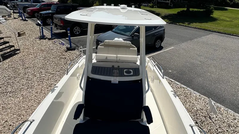 Slide: The Image of 2025 Boston Whaler 220 Dauntless boat with seating and console, parked outdoors. - 15