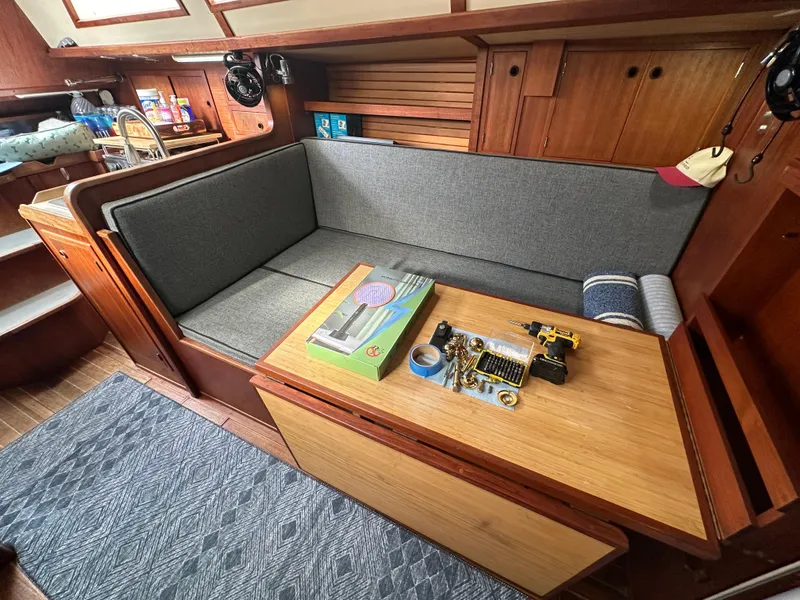 Slide: The Image of 1979 Valiant 37 sailboat interior with gray seating, wooden table, and nautical decor. - 18
