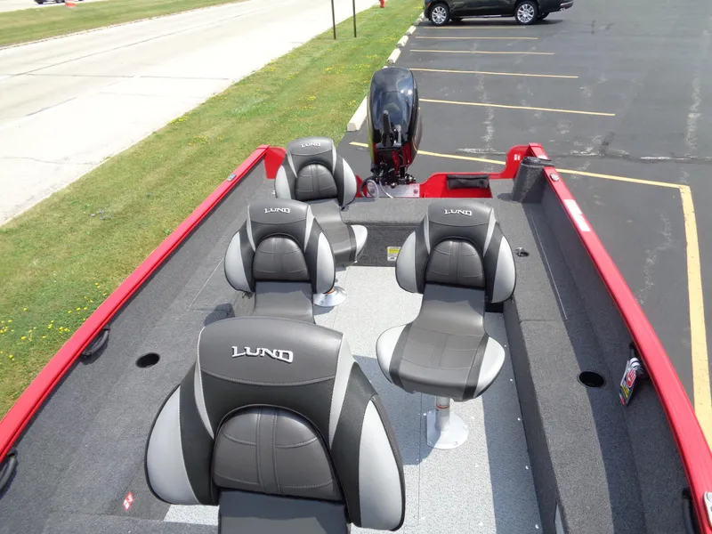 Slide: The Image of 2025 Lund 1650 Rebel XL Tiller boat interior with four seats, parked on pavement. - 7